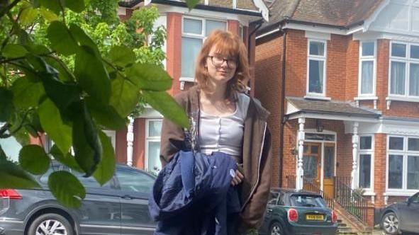 A teenage girl stands outside a house on a residential street. Image source, Clare Rogers